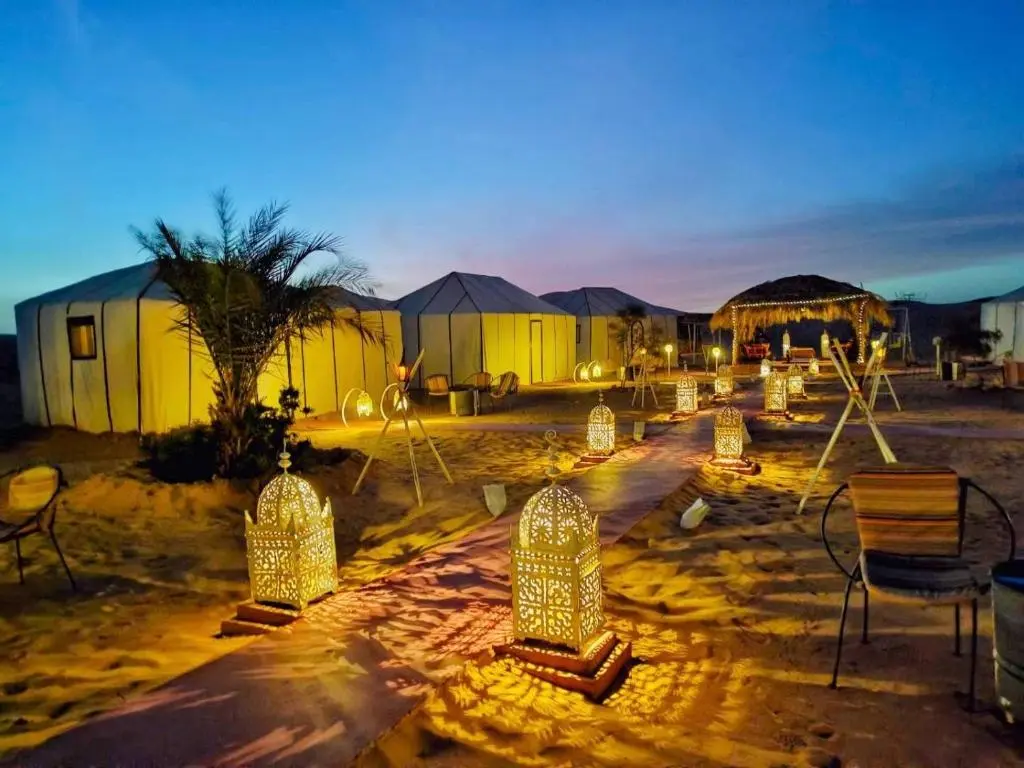 Luxurious glamping tent with king-size bed and warm lights, a stop on a 3 day desert tour from Marrakech.